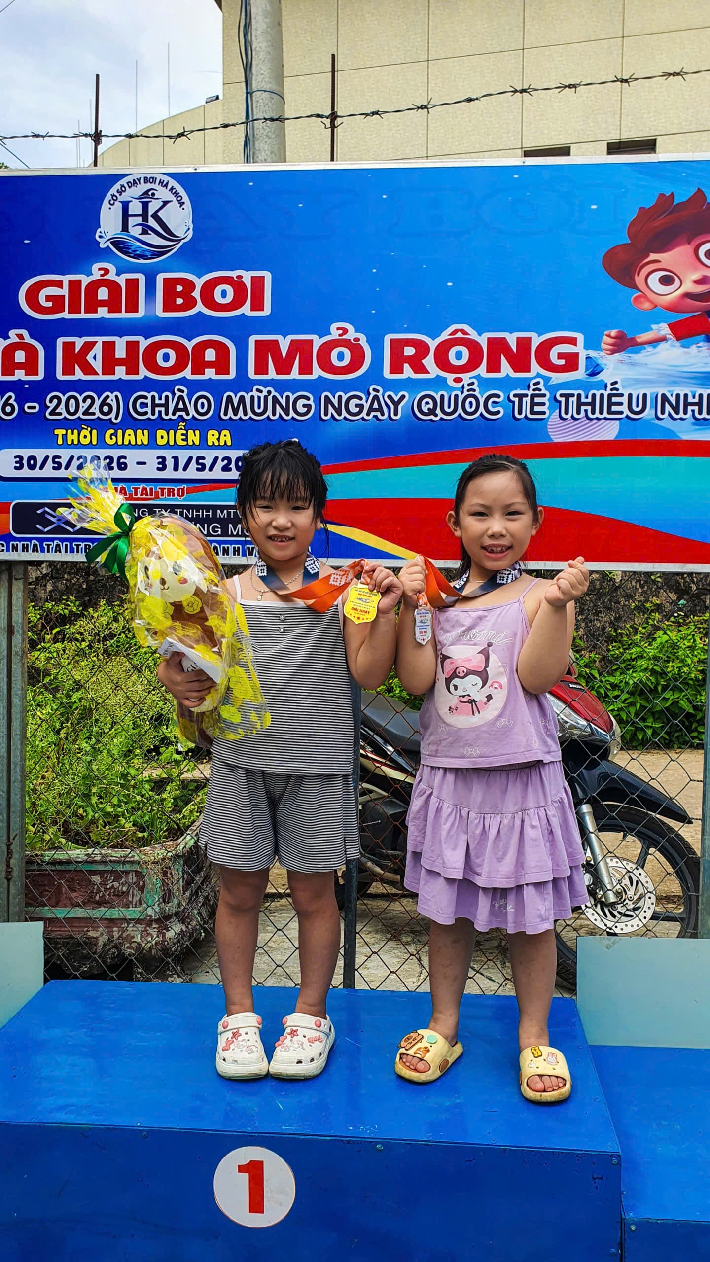 Hai vận động viên nhí khoe huy chương và phần quà tại giải bơi